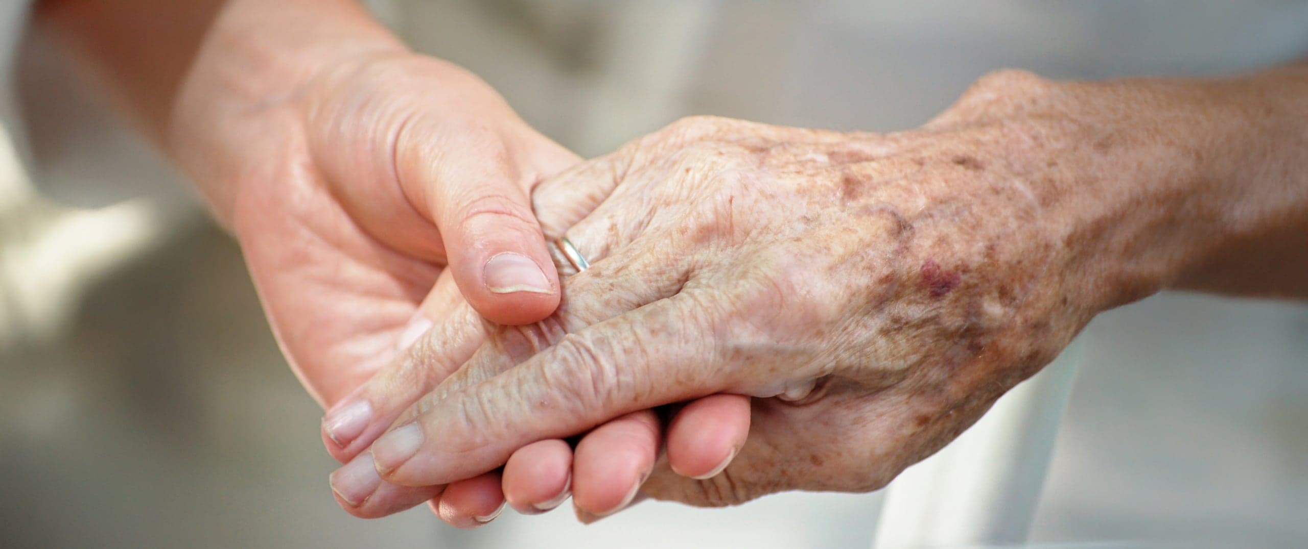 Eine junge Hand hält behutsam eine ältere Hand